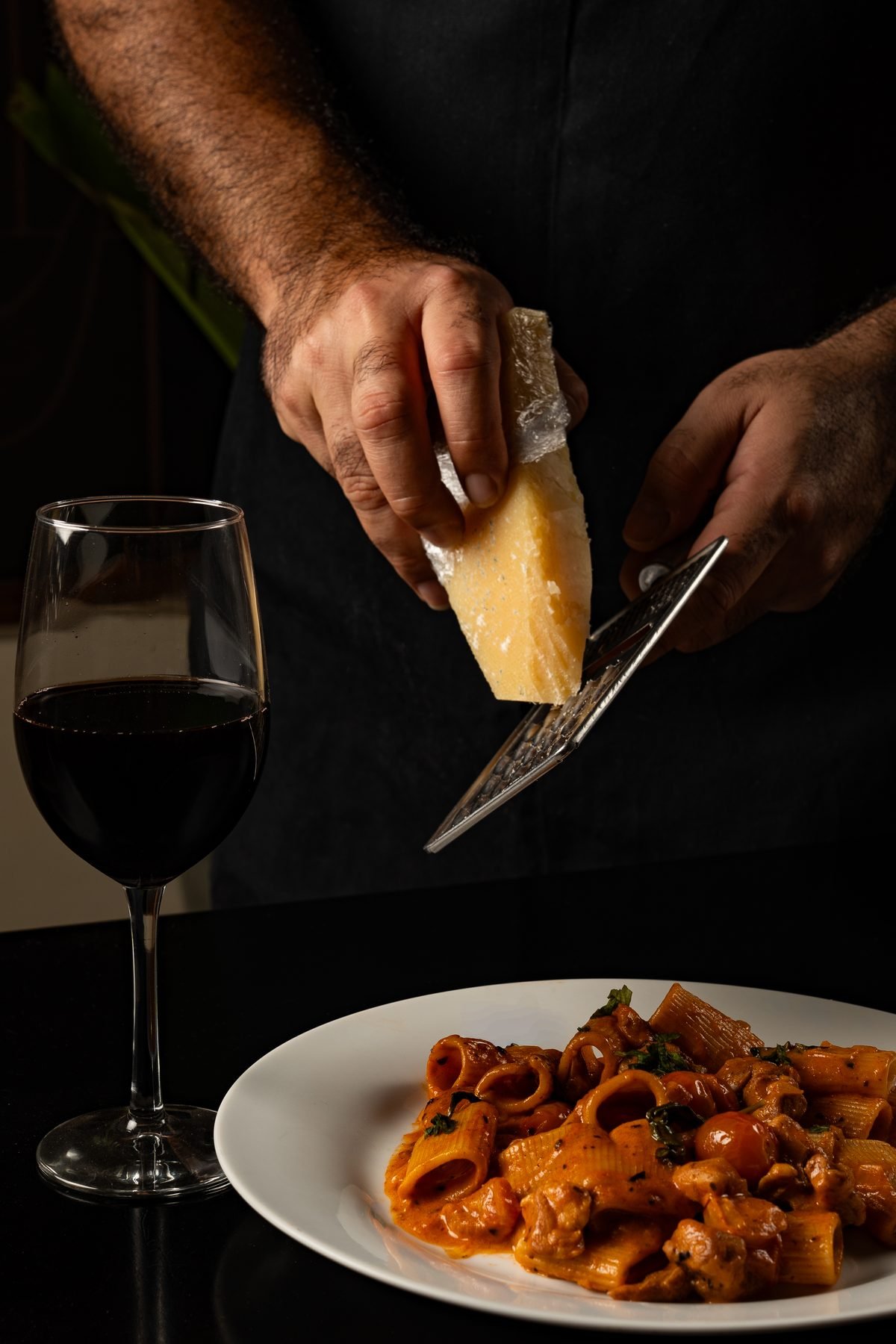 Manos rallando parmesano fresco sobre pasta